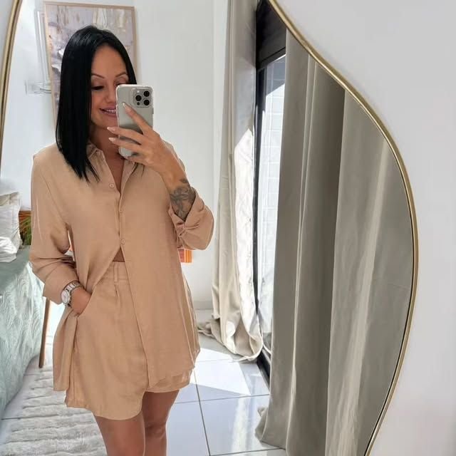 Cliente experimentando conjunto de camisa e short bege diante do espelho